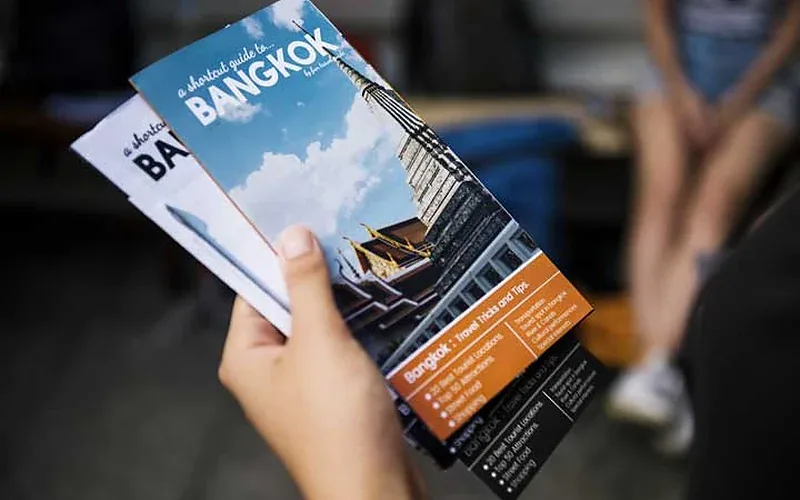 Osoba trzymająca drukowaną ulotkę turystyczną o Bangkoku